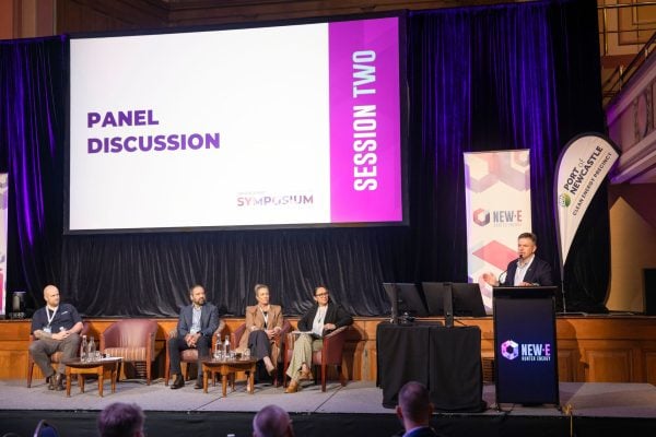 Moderator and four panelists on stage for Session Two of the Hunter New Energy Symposium, with the panel discussion title visible on the screen.