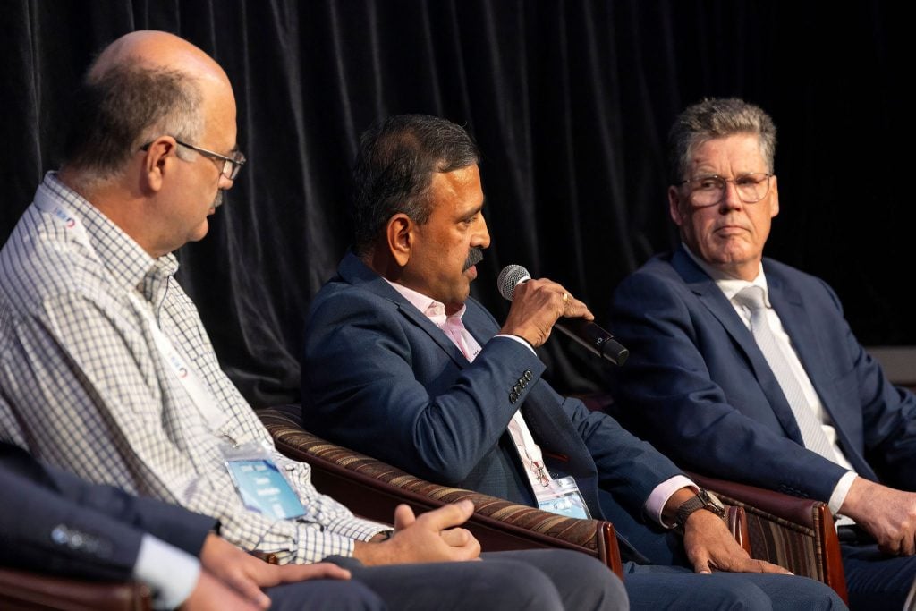 Three men seated on a stage, participating in a panel discussion.