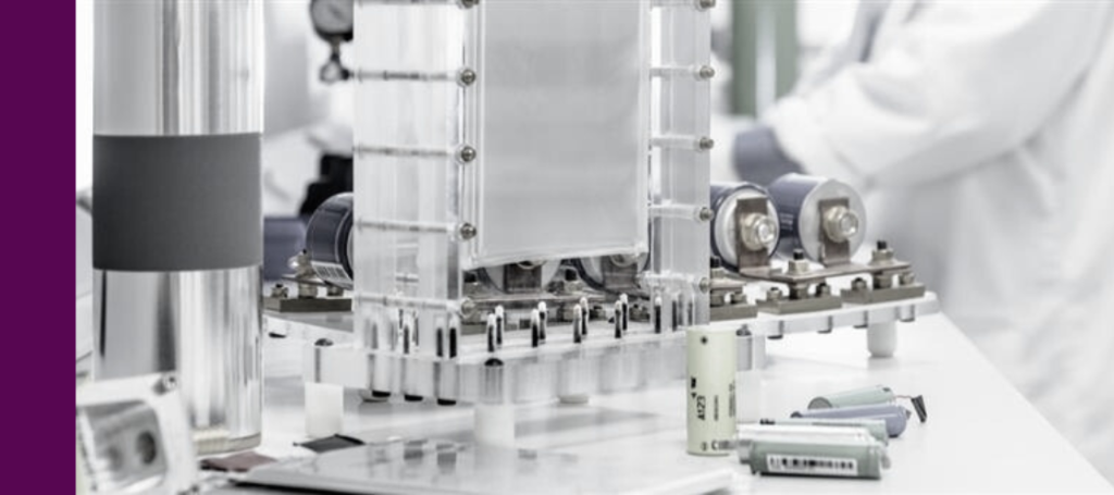 A scientific or industrial equipment, likely a battery or fuel cell prototype, resting on a clean white table in a lab setting.