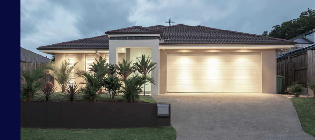 A modern, single-story suburban house illuminated at dusk or dawn.